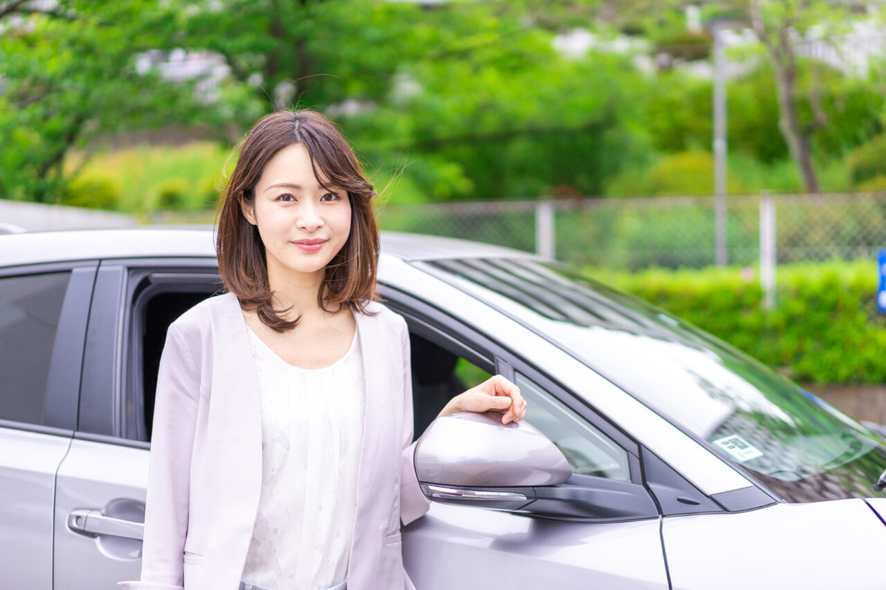 乗用車の横に立つ女性