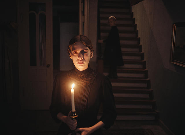 女性が燭台を持つ、映画『落下音』の場面
