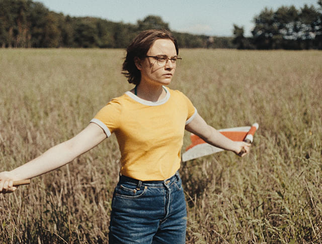 女性が旗を手にして立つ、映画『落下音』の場面